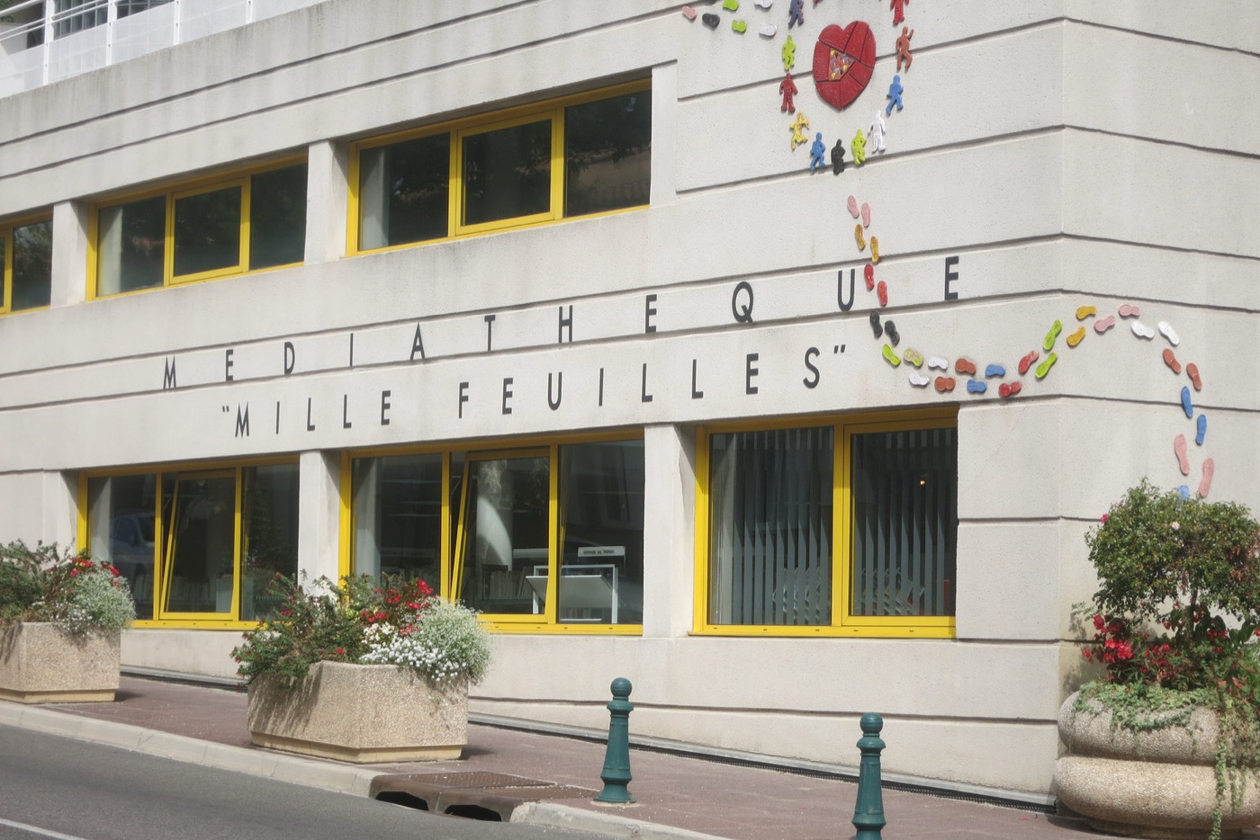 Façade de la médiathèque Mille Feuilles, avec ses fenêtres jaunes et sa fresque de personnages colorés